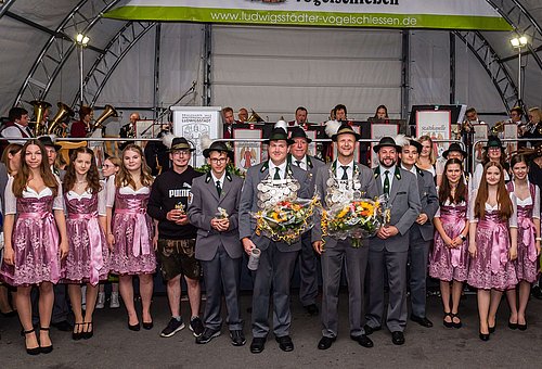Im Halbkreis stehen außen die Schützenliesel und dazwischen der neue Schützenkönig und seine Ritter. 