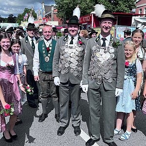 Die drei Könige (Schützenkönig, Jungkönig und Jedermannkönig) stehen nebeneinander in Tracht bzw. Uniform. Umrahmt werden sie von den Schützenliesel (6 junge Frauen in Dirndl).