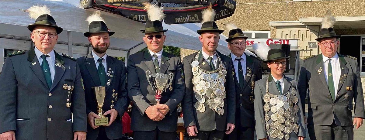 Der Schützenkönig und sein Gefolge wie Jungschützenkönig, erster Ritter und die Schützenmeister schauen lächelnd in die Kamera.