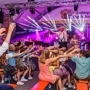 Die Gäste feiern ausgelassen im Festzelt und schwenken die Arme zur Musik in der Luft.