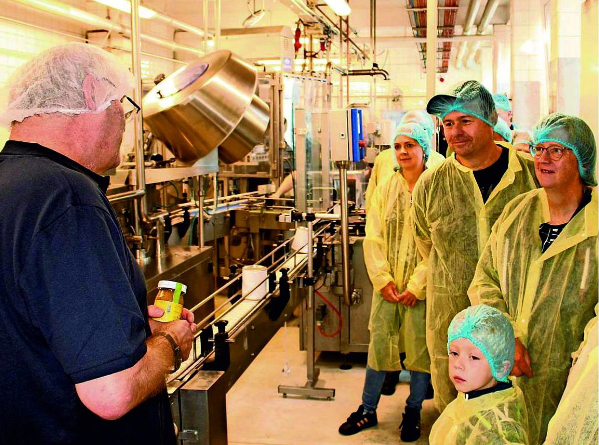 Besucher mit Schutzkleidung bestaunen die Produktionsanlagen der Wela-Werke