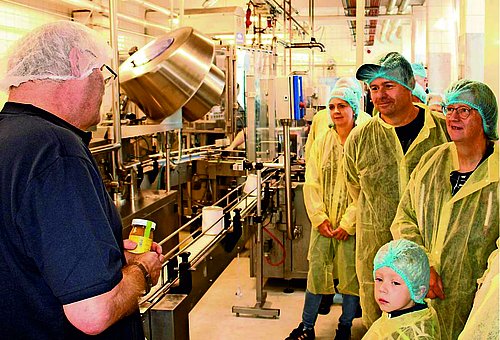 Besucher mit Schutzkleidung bestaunen die Produktionsanlagen der Wela-Werke