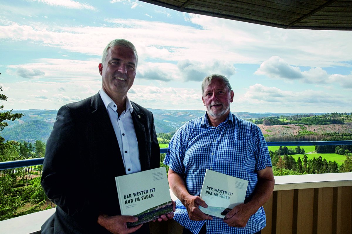 Bürgermeister Timo Ehrhardt und Siegfried Scheidig stehen auf einer Aussichtplattform und halten je ein Buch in der Hand.