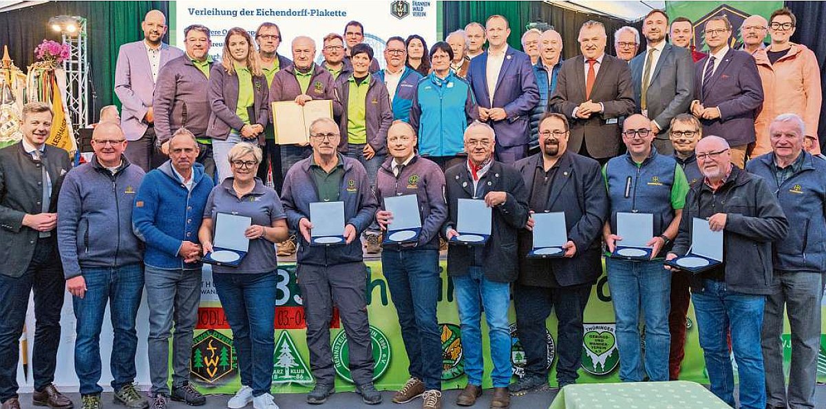 Eine große Gruppe von Menschen. Sie tragen Freizeitwanderkleidung. Viele halten eine Urkunde in der Hand. Alle lächeln in die Kamera.