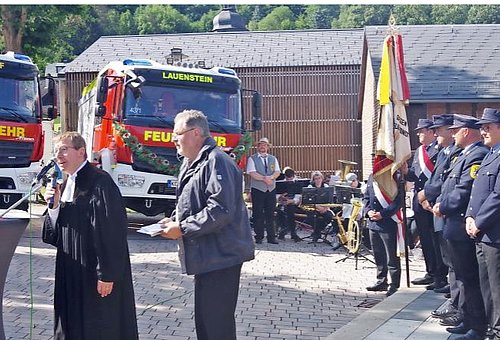 Auf dem Bild sind im Hintergrund zwei neue Feuerwehrfahrzeuge LF 10 zu sehen. Im Vordergrund Pfarrer und Pastoralreferent sowie Feuerwehrkameraden.