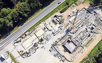 Eine große Baustelle von oben. Man sieht planierte Flächen, Schwimmbecken, Gebäudemauern.