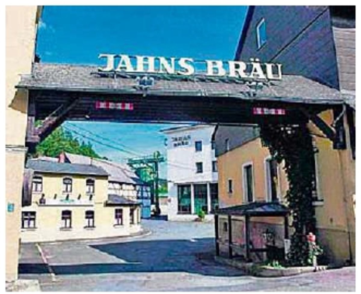 ein Tor aus Holz zwischen zwei Häusern zeigt den Eingang zu einem Betriebsgelände. Auf dem Dach des Tores steht "Jahns Bräu".