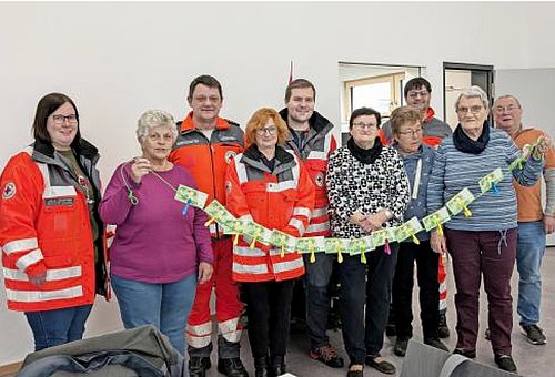 Eine Gruppe von Menschen lachen in die Kamera. Sie halten eine Leine an der 100-Euro Scheine hängen.